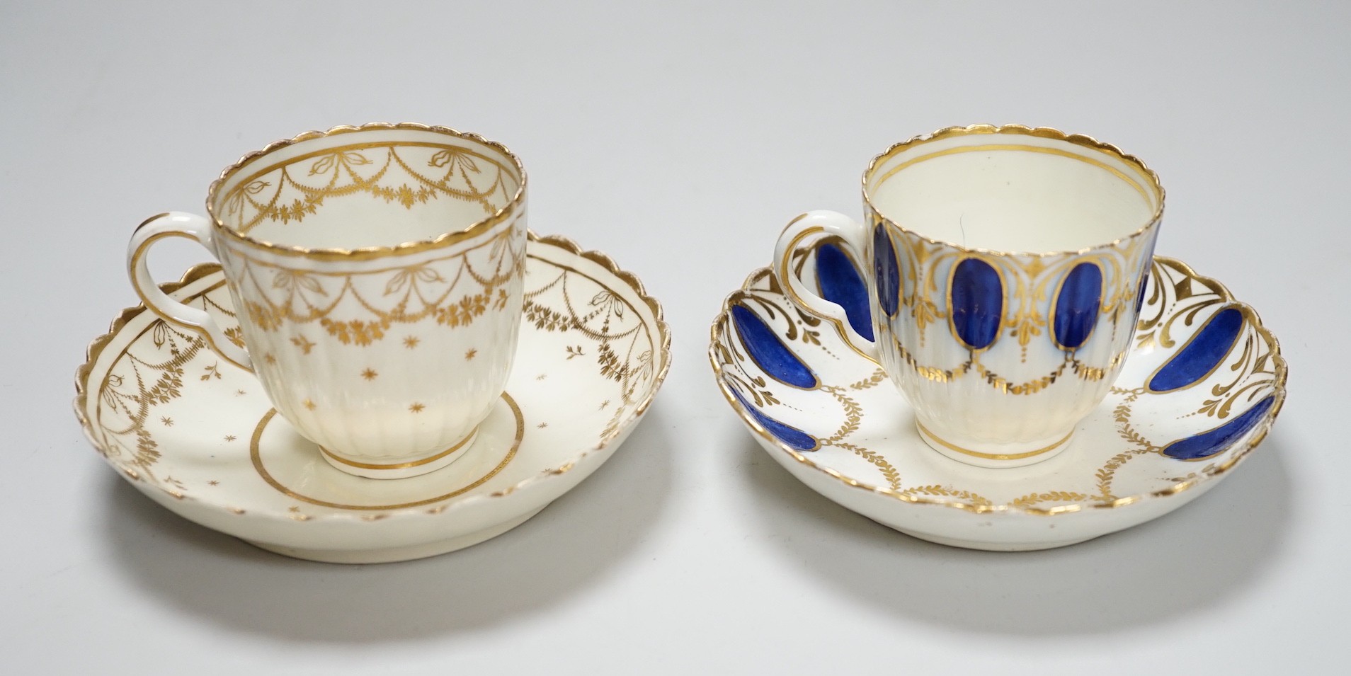 An 18th century Caughley coffee cup and saucer with blue pendants from gilt leafy swags and an 18th century Caughley coffee cup and saucer with an elaborately gilded border, both probably decorated at Chamberlains premis
